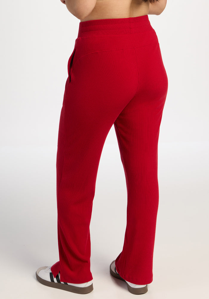 Model in Woolx Luca Ribbed Pants - Maraschino Cherry, shown from the back, with slide sandals on white background.