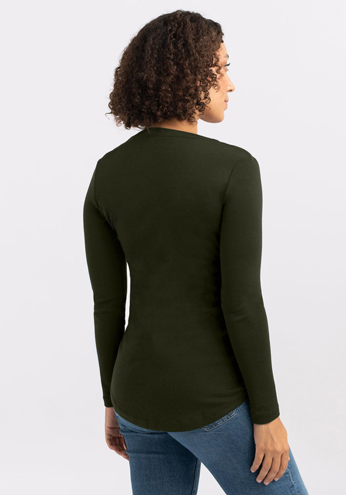 Woman with curly hair wears the Woolx Eva Tunic - Duffel Bag and blue jeans, facing away from the camera.