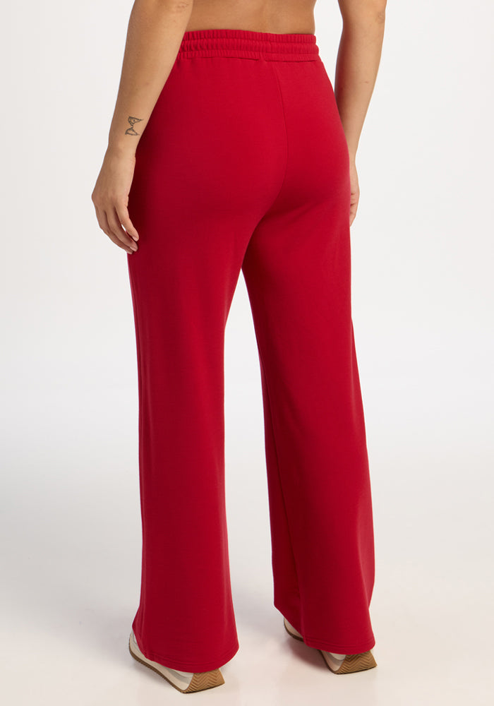 Person in Woolx Eloise Wide Leg Pants - Maraschino Cherry, relaxed fit, barefoot, seen from behind on white backdrop.
