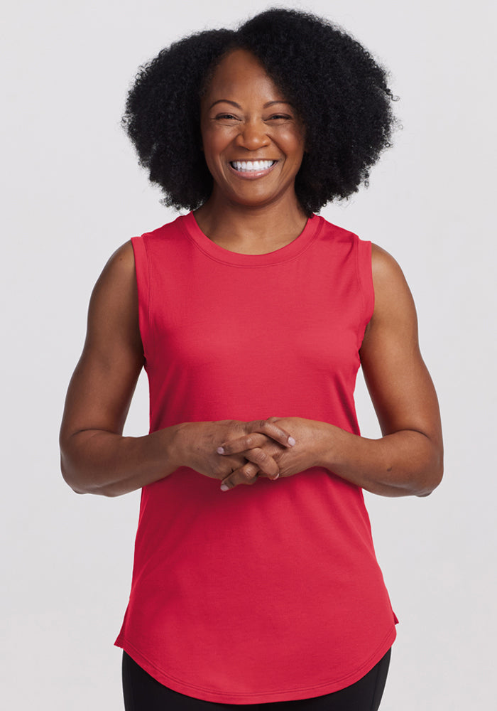 Smiling woman with curly hair wears the Woolx Bella Tunic Top in Berry Ice Pop, standing against a white background. 