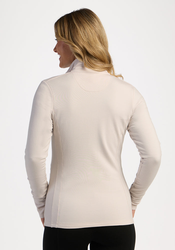 Woman with long blonde hair wears the Woolx Finley Zip Up Sweatshirt in ecru, shown from the back.
