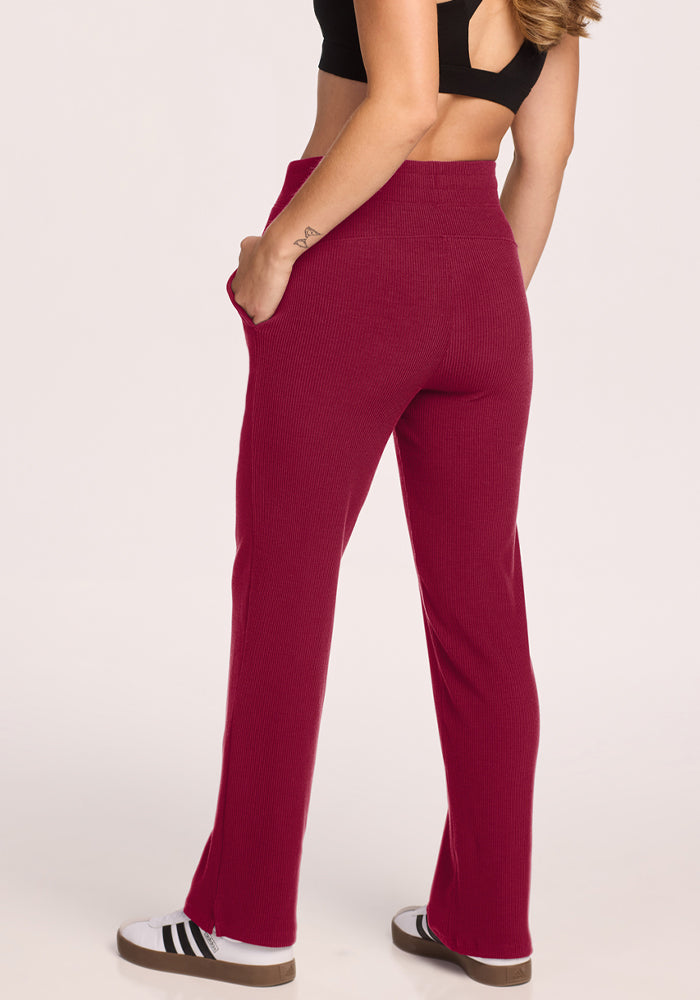 Woman faces away in black crop top and Woolx Luca Petite Pants - Beet Red, hands in pockets, wearing sneakers.