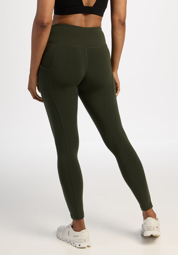 Person wearing Woolx Piper Pocket Leggings - Duffel Bag, a black sports bra, and white sneakers on a white background.