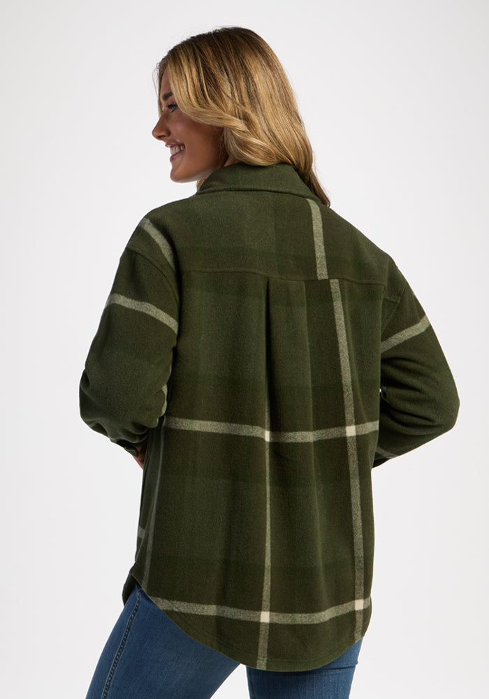 Woman smiling in Woolx Sawyer Shacket - Driftwood Fern Plaid and blue jeans, facing away on a white background.
