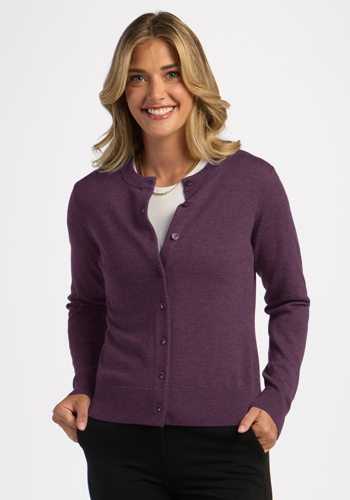 Smiling person in the Woolx Caitlin Sweater - Purple Iris, over a white top and black pants, on a white background. | Ariana is 5'11", wearing a size S