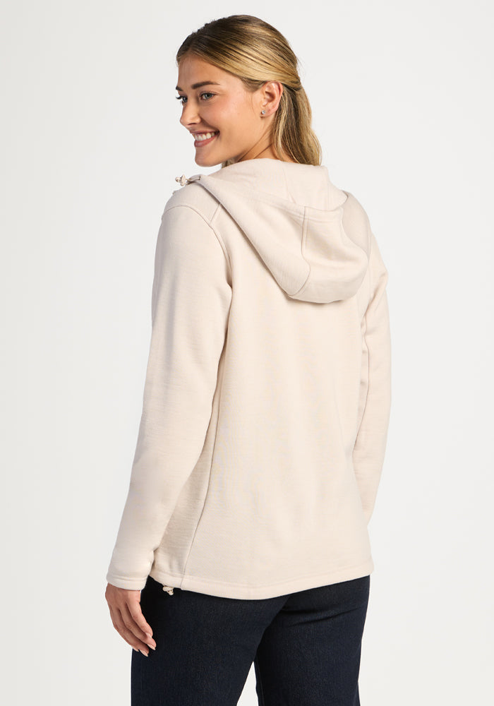 A woman seen from the back wearing a light-colored Cubby Hooded Sweatshirt - Ecru and dark pants.