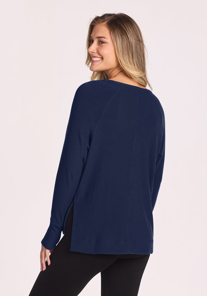Woman smiling in Woolx Ainsley Sweater - Ocean Cavern, shown from the back against a light background.