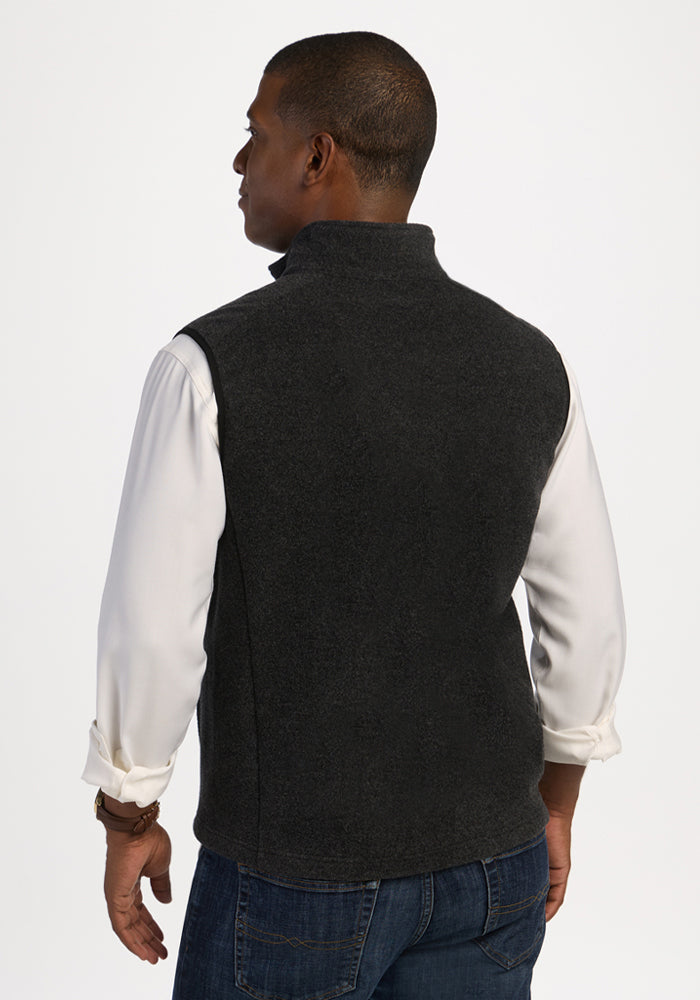 A man seen from the back wearing a carbon black Everest Vest over a white button-down shirt and jeans.
