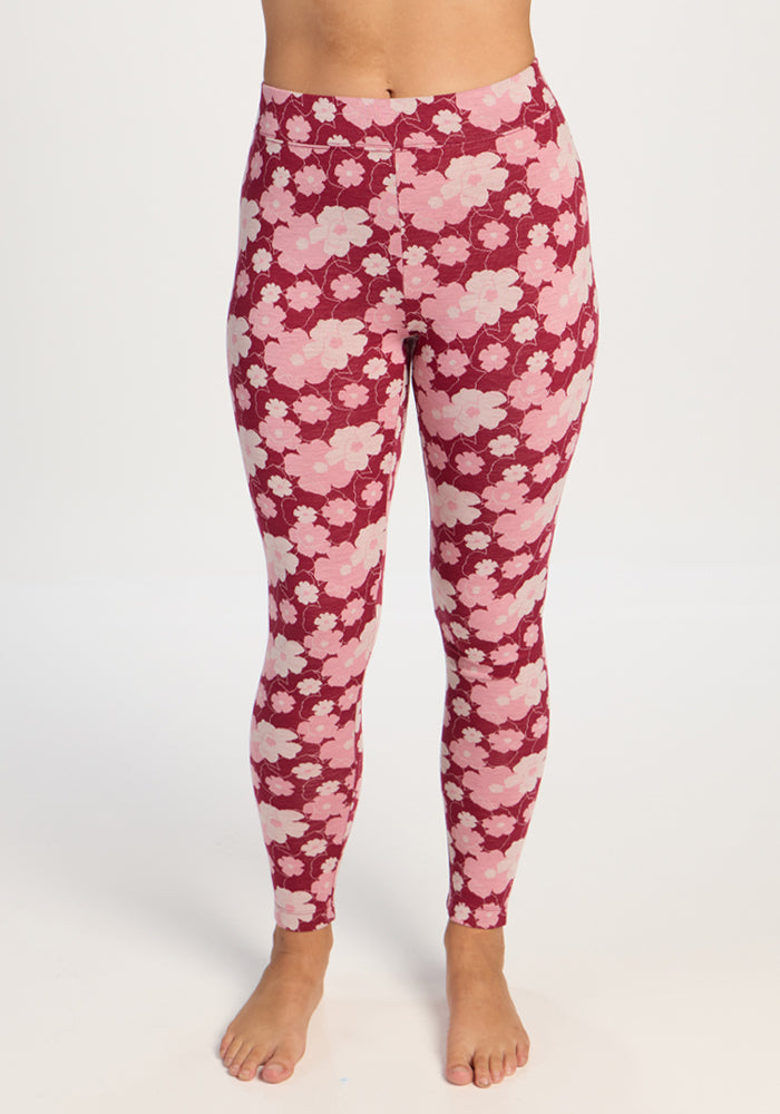 A person wears Woolx Taylor Baselayer Leggings - Floral Crush, standing barefoot before a plain white background. 