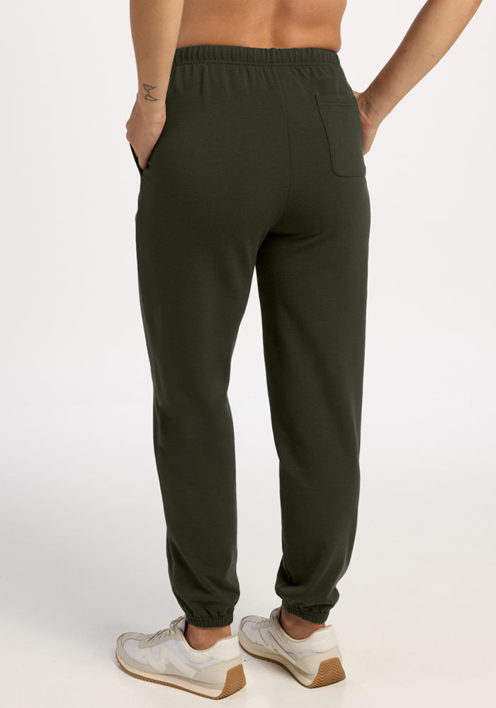 Person wearing Woolx Juliette Joggers in Duffel Bag, white sneakers, hands in pockets, shown from the back.