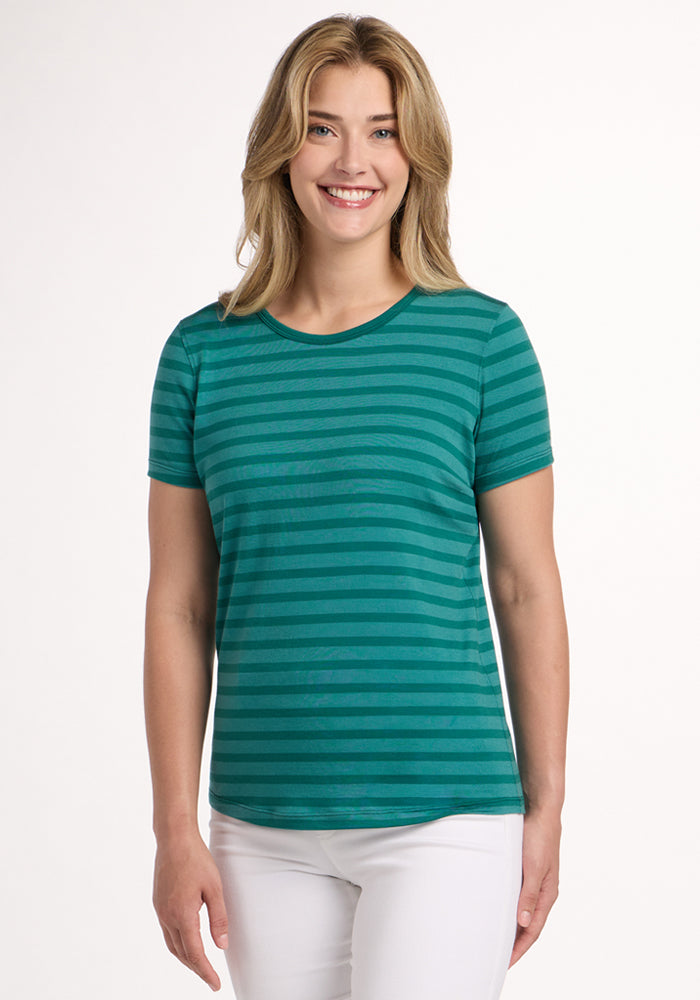 Smiling woman in a Woolx Liza Crew Neck Tee - Woodland Stripe and white pants stands against a plain white background. 