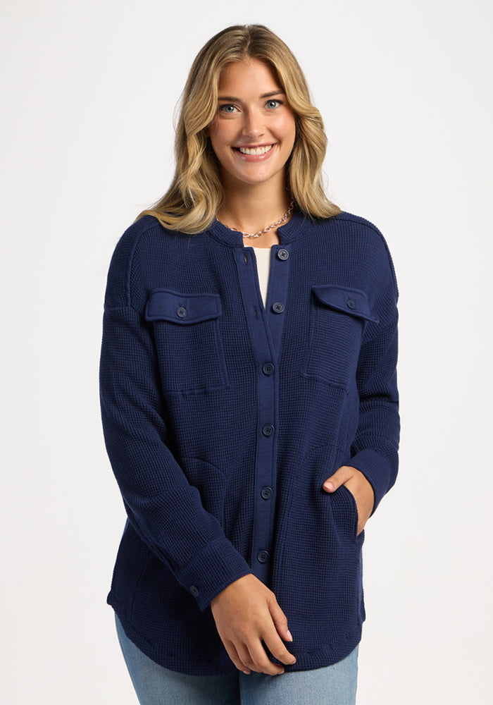 Smiling woman in a Woolx Oaklynn Waffle Shacket - Ocean Cavern, hand in pocket, against a white background. | Ariana is 5'11", wearing a size S