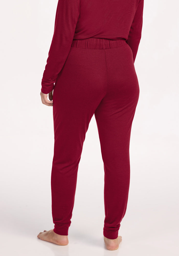 A person seen from behind wearing beet red Mary Kate Lounge Pants in merino wool with an elastic waistband and cuffs.