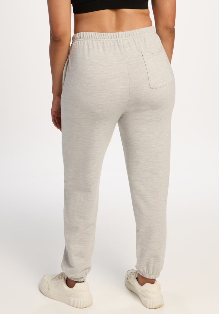 A person in Woolx Juliette Joggers - Light Ash and white sneakers, seen from behind on a plain white background.