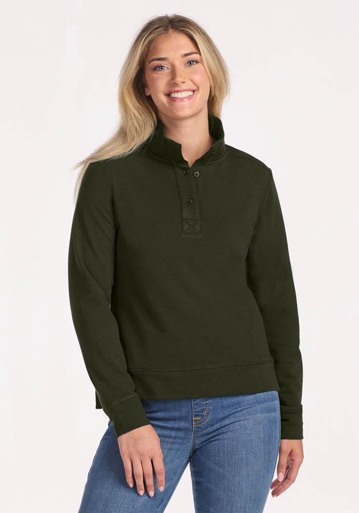 Smiling person wears Woolx Annie 3 Button Pullover in Duffel Bag and blue jeans, against a light background. 