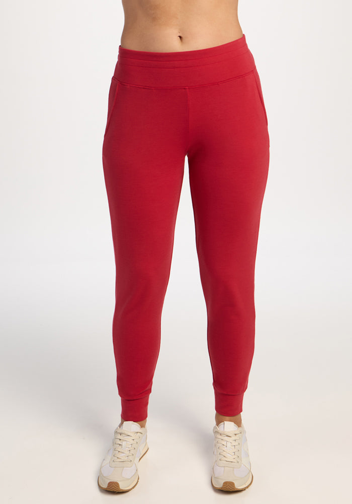 Model wears Woolx Madden Petite Joggers in Maraschino Cherry with white sneakers, posed against a plain white background.