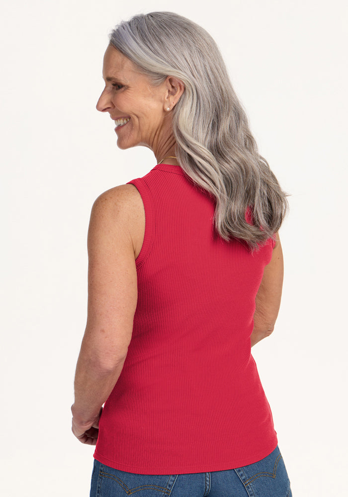 Older woman with long gray hair smiles in the Woolx Raegan Ribbed Tank Top - Berry Ice Pop, sleeveless and red.