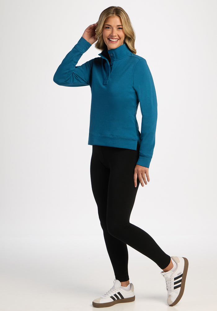 Woman in Woolx Annie 3 Button Pullover - Blue Pine smiles and poses against a plain white background.