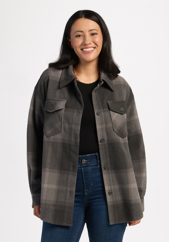 Woman in Woolx Sawyer Shacket—Volcanic Ash Plaid—over black top, blue jeans, smiling against a white background. | Sarah is 5'8", wearing a size S