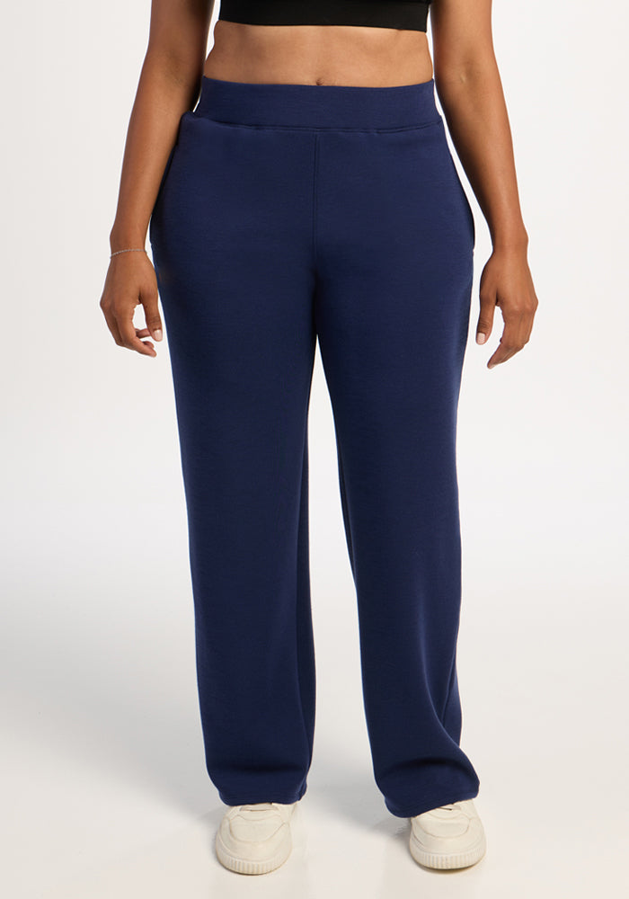 Model in Woolx Bree Lounge Pants - Ocean Cavern with white sneakers and a black crop top stands against a plain backdrop. 