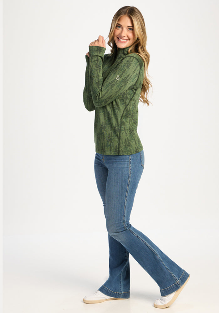 Woman in Woolx Emi 1/4 Zip - Forest Friends and blue jeans smiles, standing sideways against a white background.