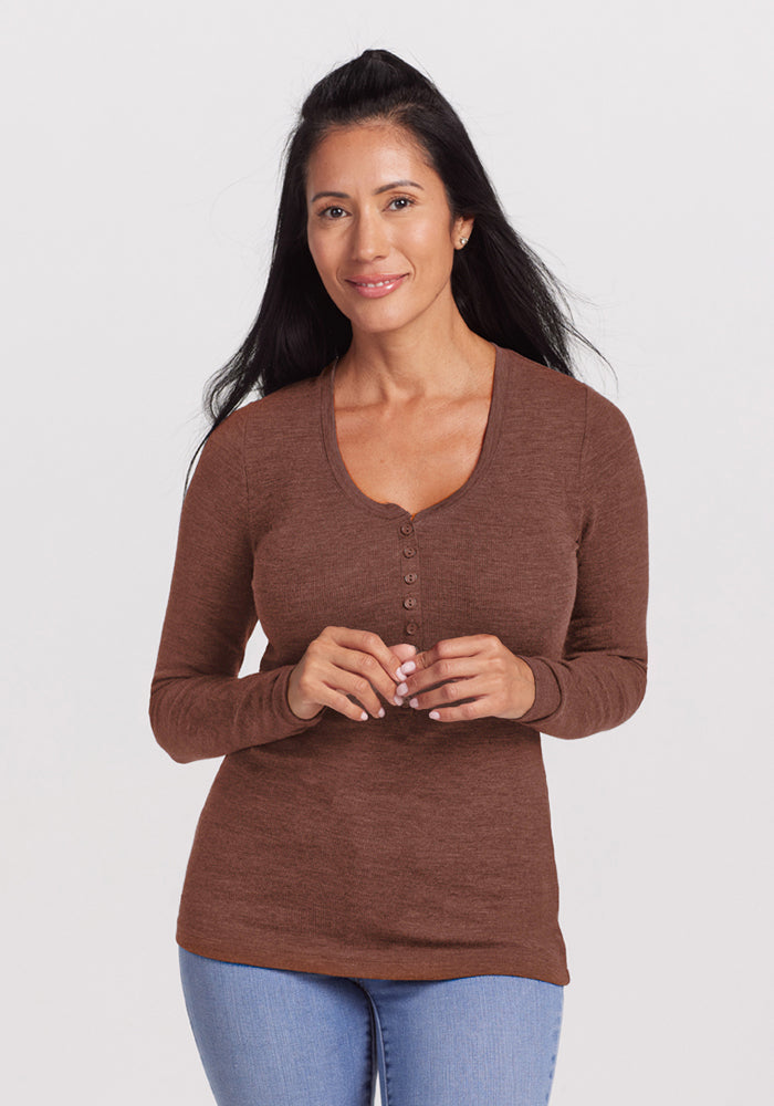 Woman with long dark hair in Woolx Reese Ribbed Henley - Sable Heather and jeans stands against a plain light background. 