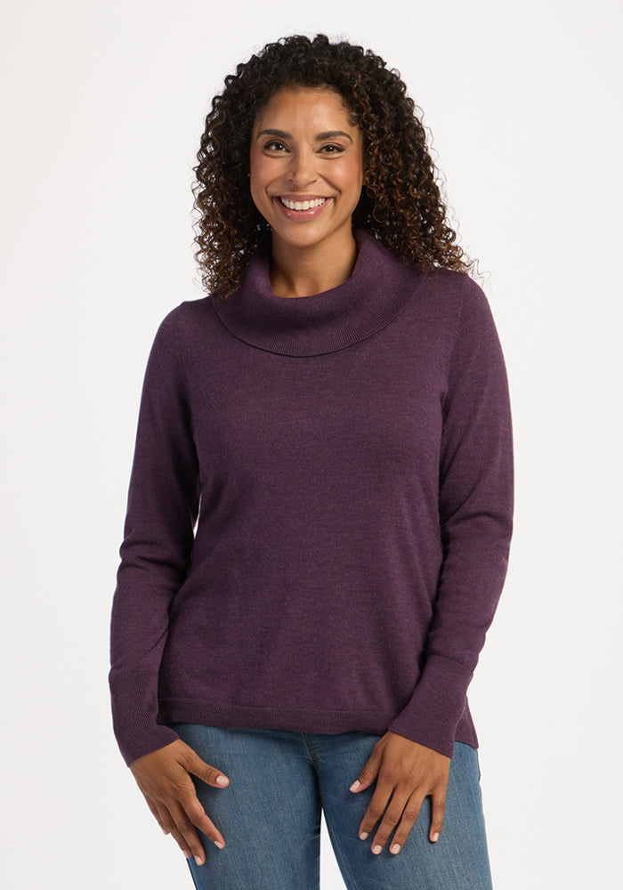 Woman with curly hair smiles in the Woolx Josie Cowl Neck Sweater in Purple Iris and blue jeans. 