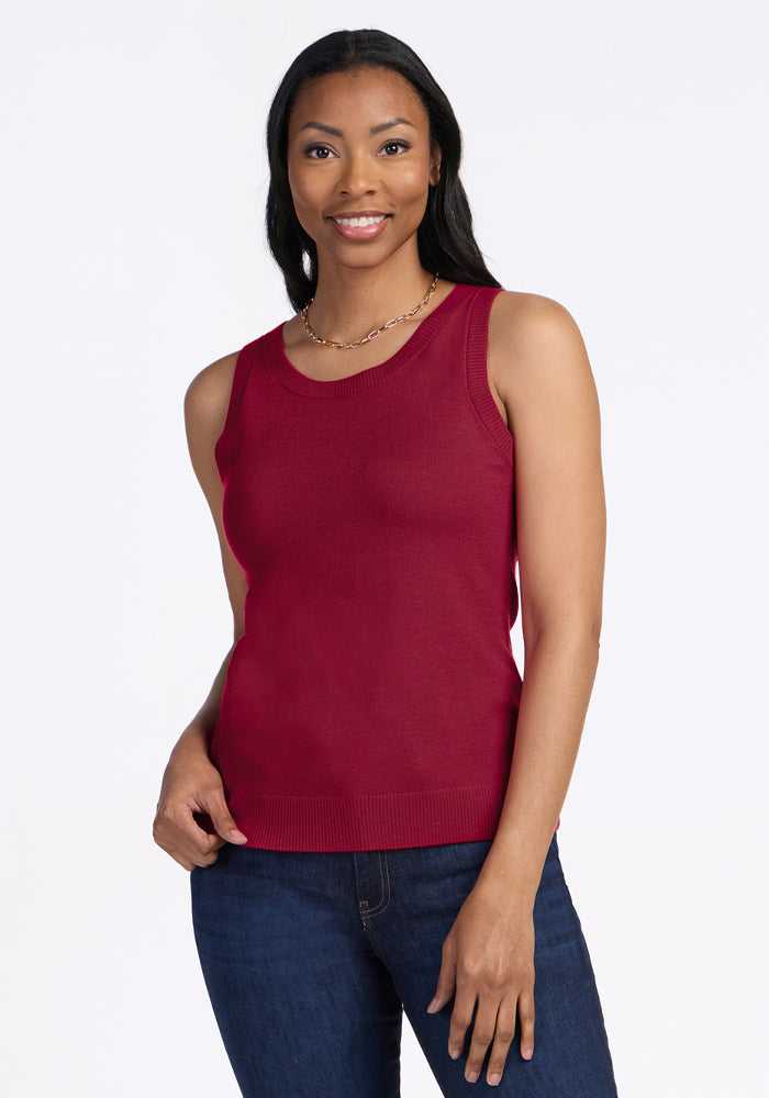 Woman wears Woolx Chessy Tank Top in Beet Red and jeans, smiling against a plain white background. 