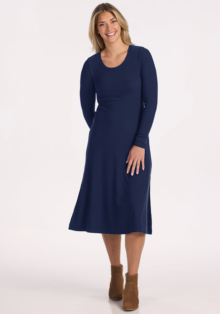 Woman in the Woolx Caroline Ribbed Twirl Dress - Ocean Cavern, smiling against a plain backdrop.