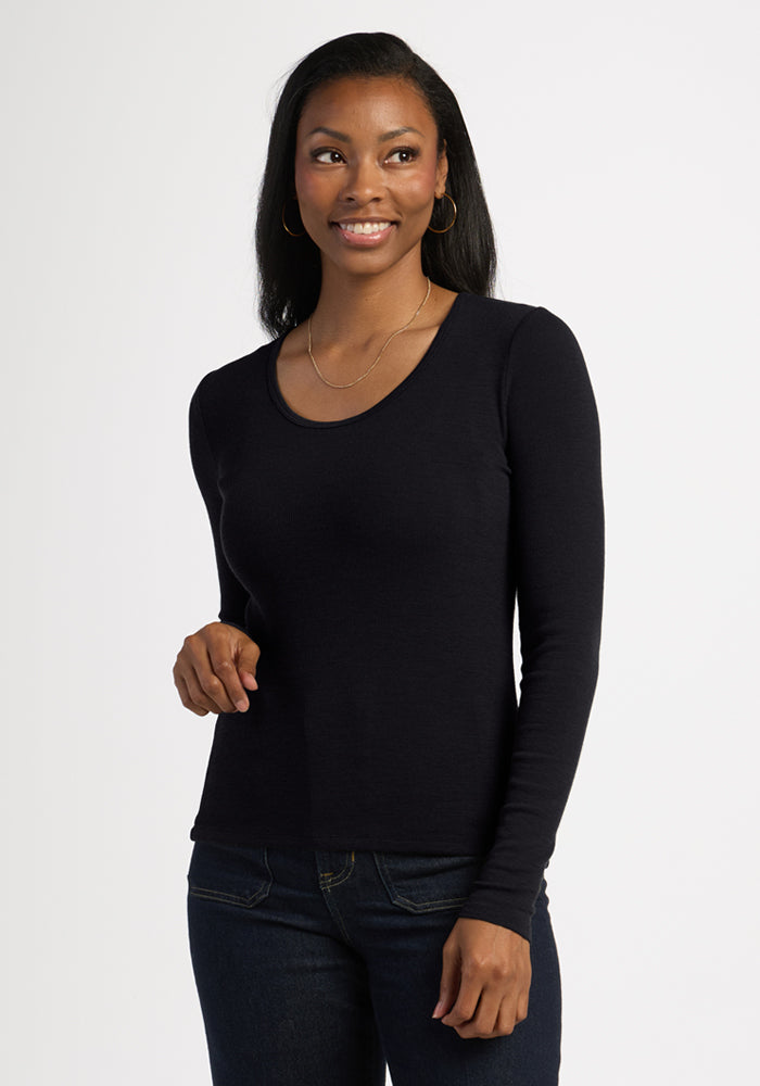 Woman with long dark hair smiles in the Woolx Katie Ribbed Long Sleeve - Black, styled with jeans against a plain backdrop. | Jade is 5’10”, wearing a size S