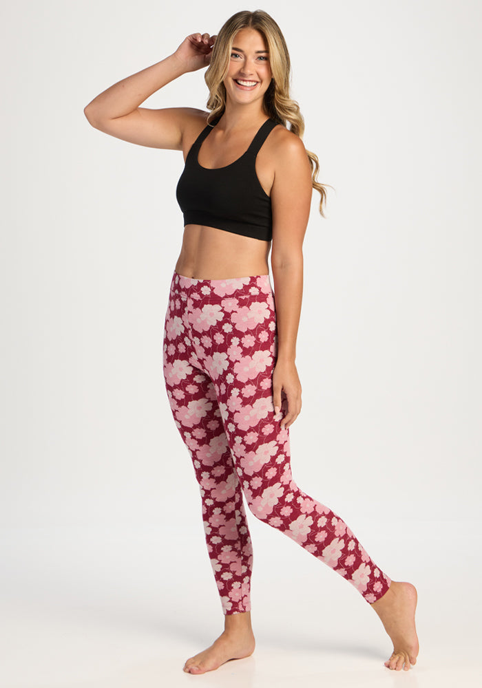 Smiling woman in Woolx Taylor Baselayer Leggings - Floral Crush poses barefoot against a white background.