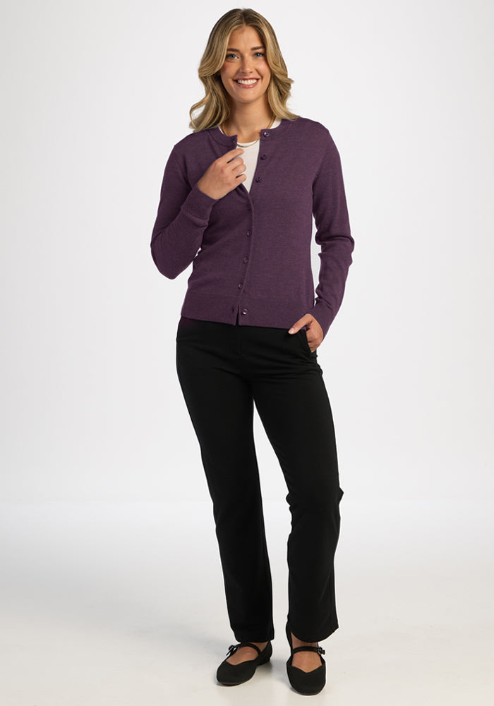 Smiling woman wears Woolx Caitlin Sweater in Purple Iris, black pants, and flats against a white background.
