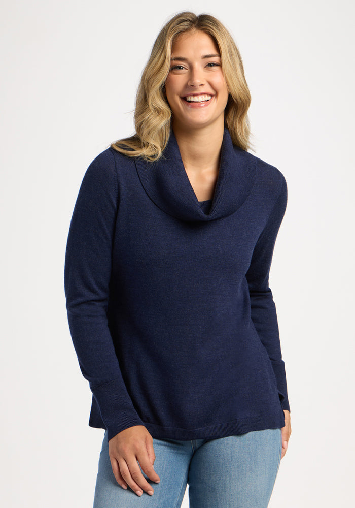 Smiling woman in Woolx Josie Cowl Neck Sweater - Ocean Cavern with jeans, against a plain white background. 