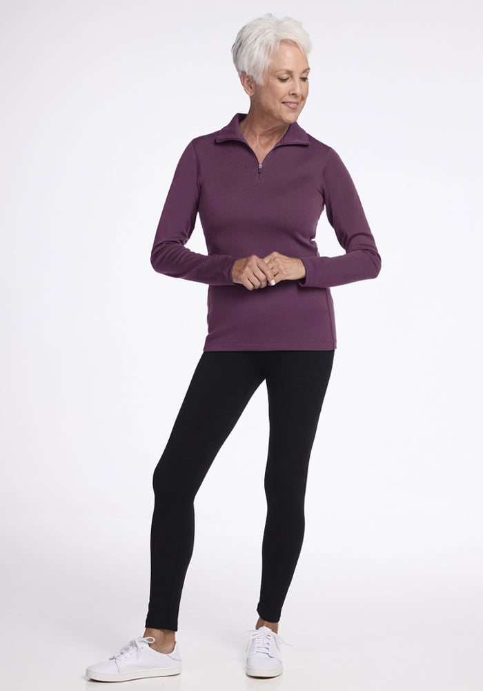Smiling older woman in Woolx Brooke 1/4 Zip - Purple Iris, black leggings, and white sneakers, standing casually.