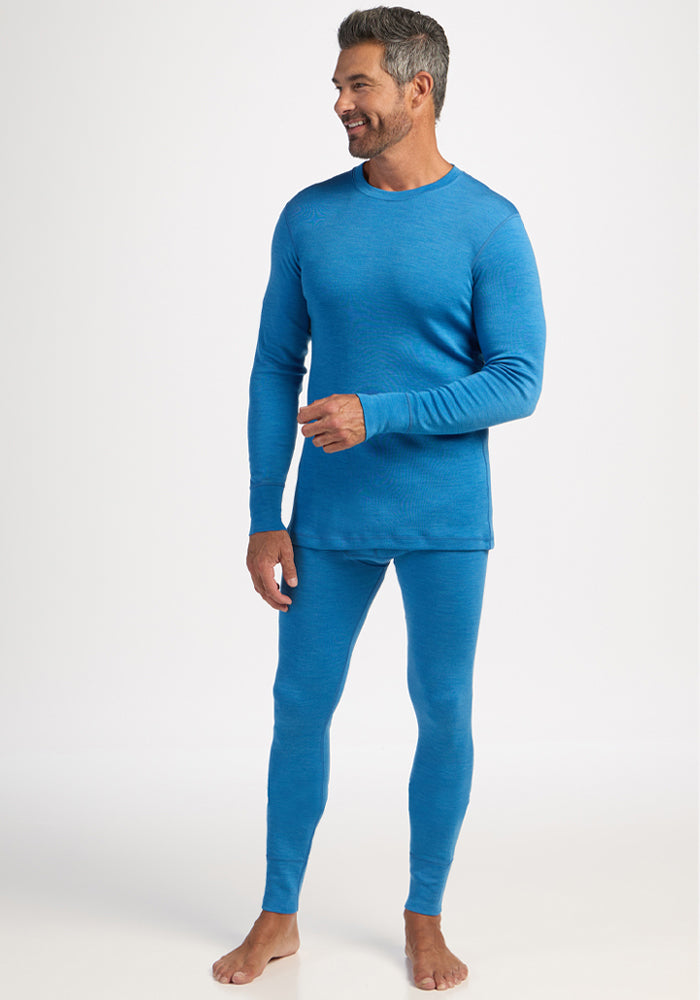 Barefoot man in Woolx Explorer Base Layer - Blue Razz stands against a plain white background.