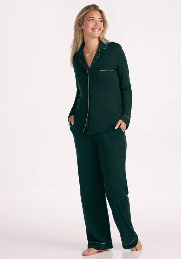 A woman in a deep pine Woolx Harper FeatherTouch® Pajama Set with long sleeves and wide-leg Merino wool pants. 