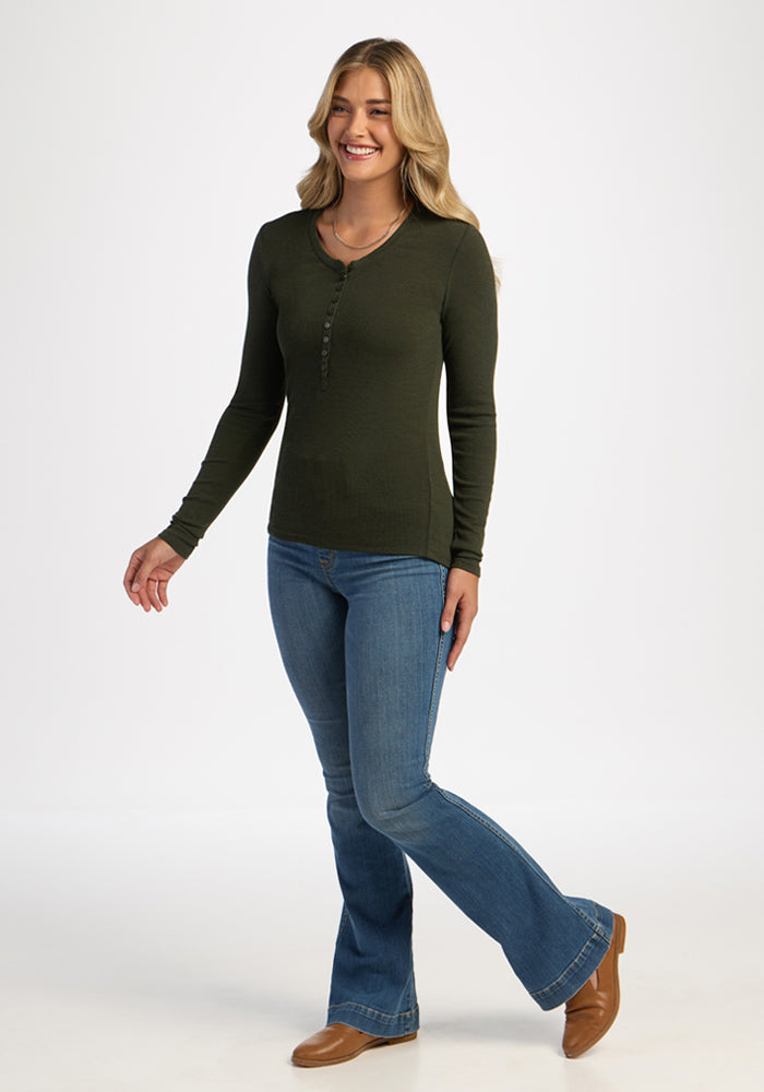 Woman in a Woolx Reese Ribbed Henley - Duffel Bag, blue jeans, and brown boots smiling against a white background.