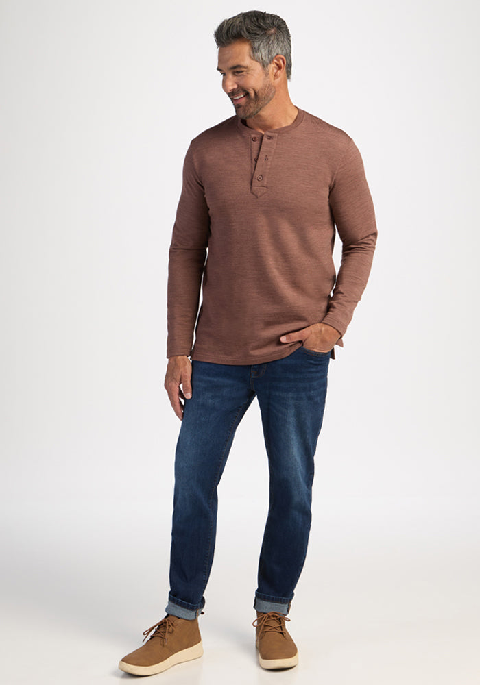 Smiling man in Woolx Jackson Henley - Sable Heather, blue jeans, and tan shoes stands against a white background.