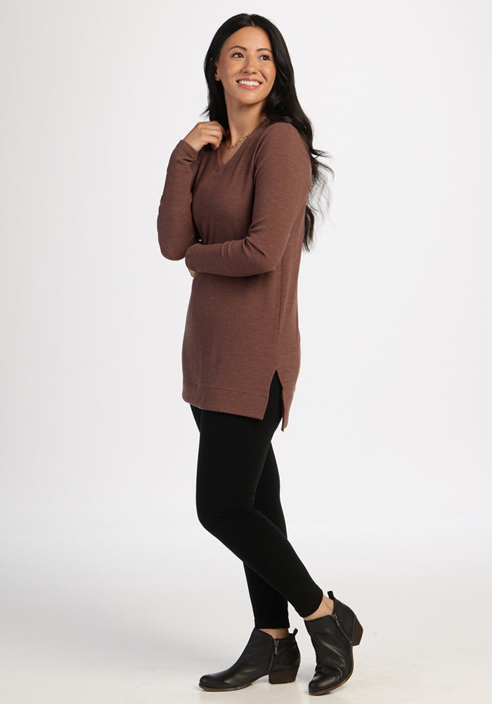 Woman in the Woolx Evie Ribbed Tunic in Sable Heather, wearing black leggings and boots, smiles brightly.
