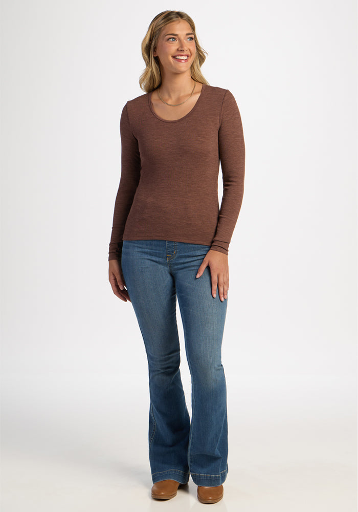 Woman wearing Woolx Katie Ribbed Long Sleeve in Sable Heather, blue jeans, and brown shoes stands smiling.