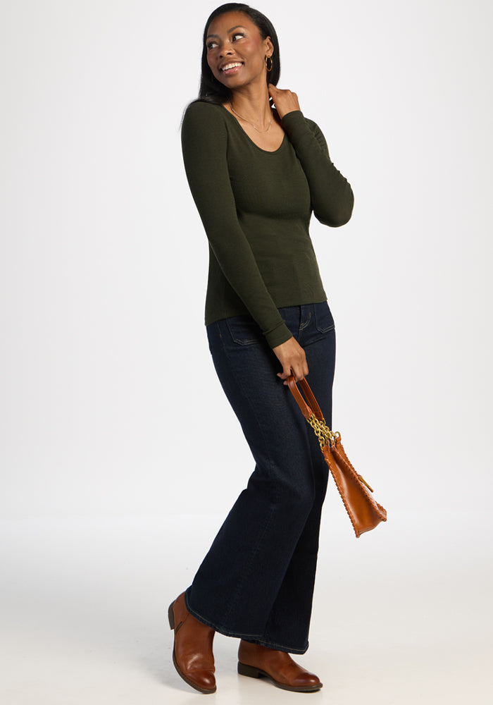 A woman in the Woolx Katie Ribbed Long Sleeve - Duffel Bag smiles, pairing it with jeans, boots, and a brown handbag.
