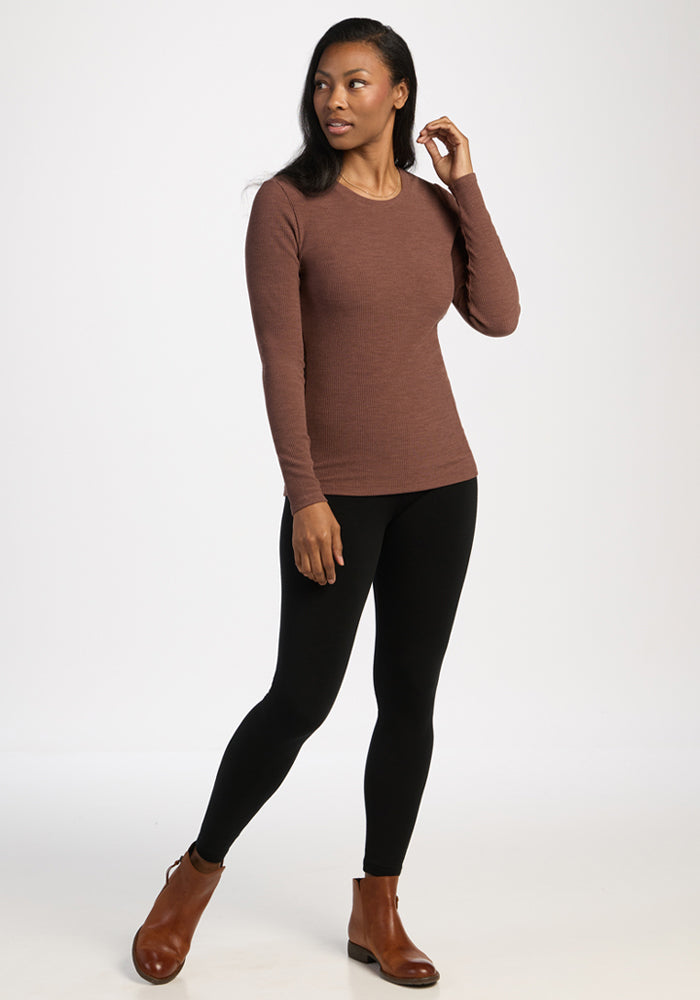Woman in a Woolx Hadley Ribbed Crew - Sable Heather, black leggings, and brown boots stands against a white background.