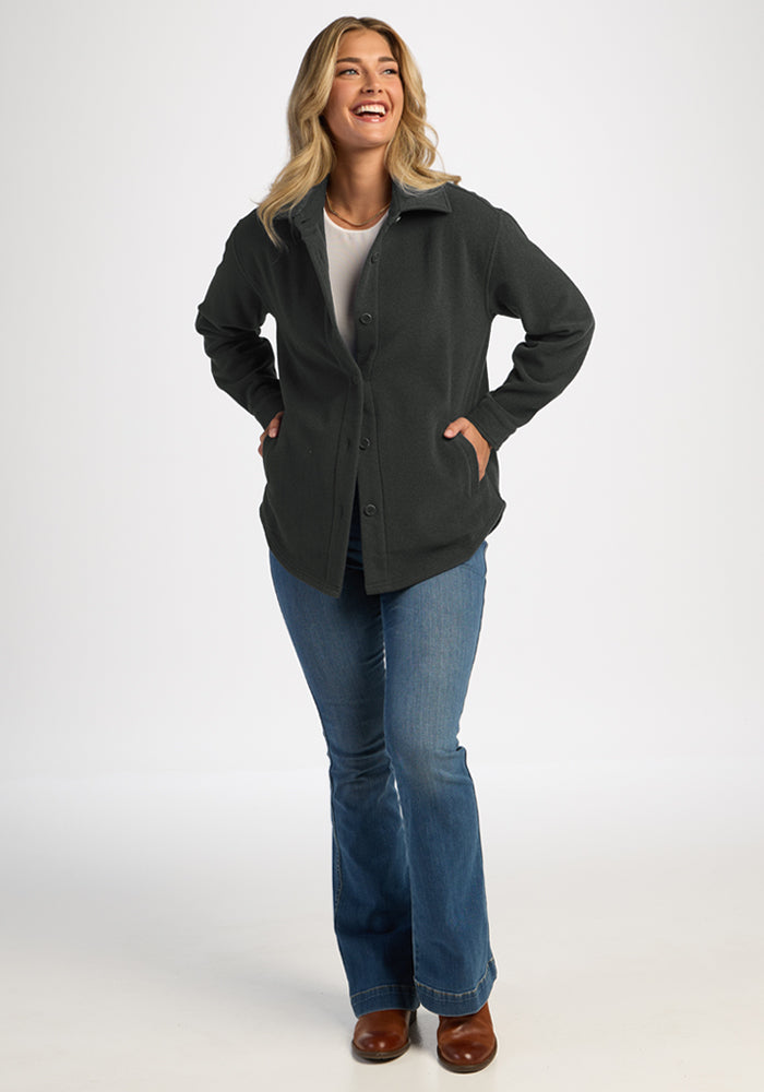 Smiling woman in Woolx Jovie Shacket—Volcanic Ash: a warm, odor-resistant Merino wool layer, hands in pockets.