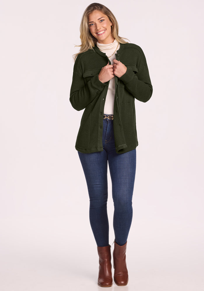 Woman in a Woolx Oaklynn Petite Waffle Shacket smiles in blue jeans, white turtleneck, and brown boots.