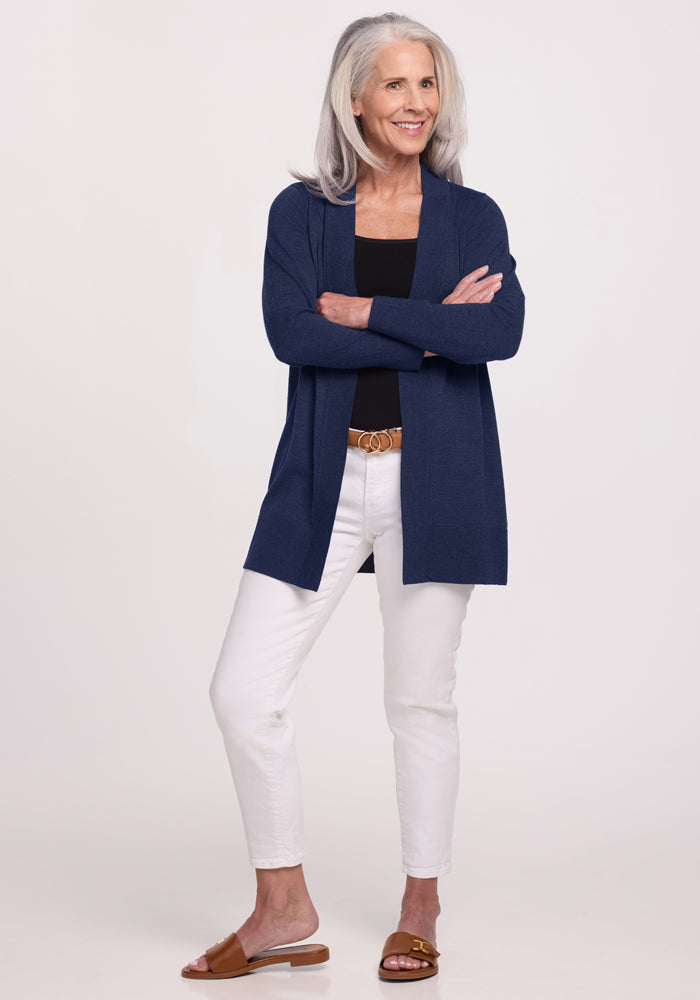 Confident older woman in Woolx Macie Sweater - Ocean Cavern, black top, white pants, and brown sandals.