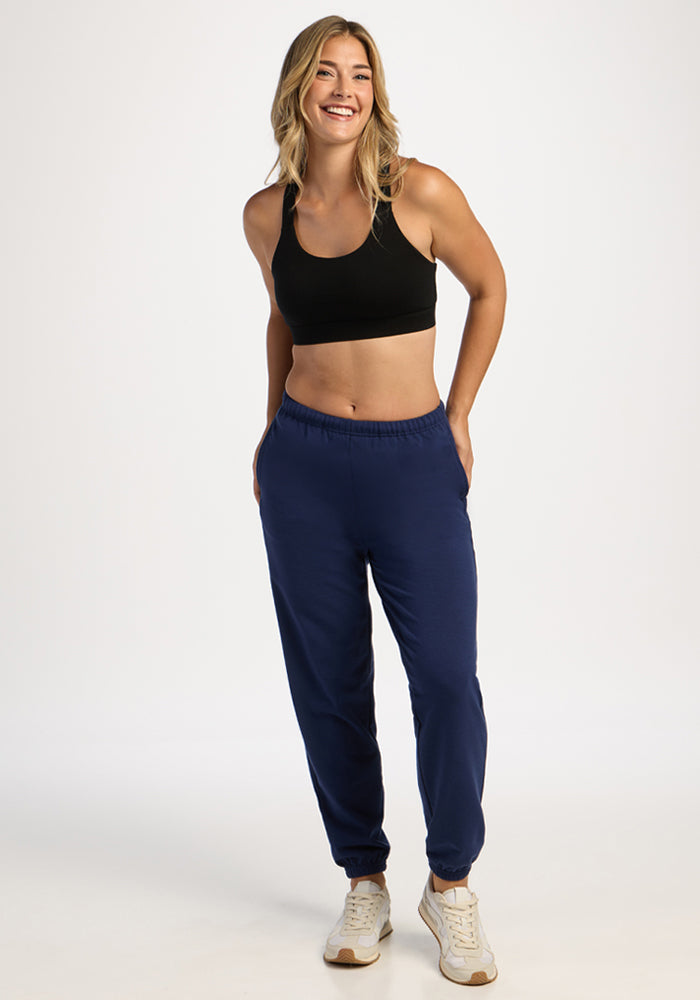 Woman in Woolx Juliette Joggers - Ocean Cavern smiles, hands in pockets, against a plain background.