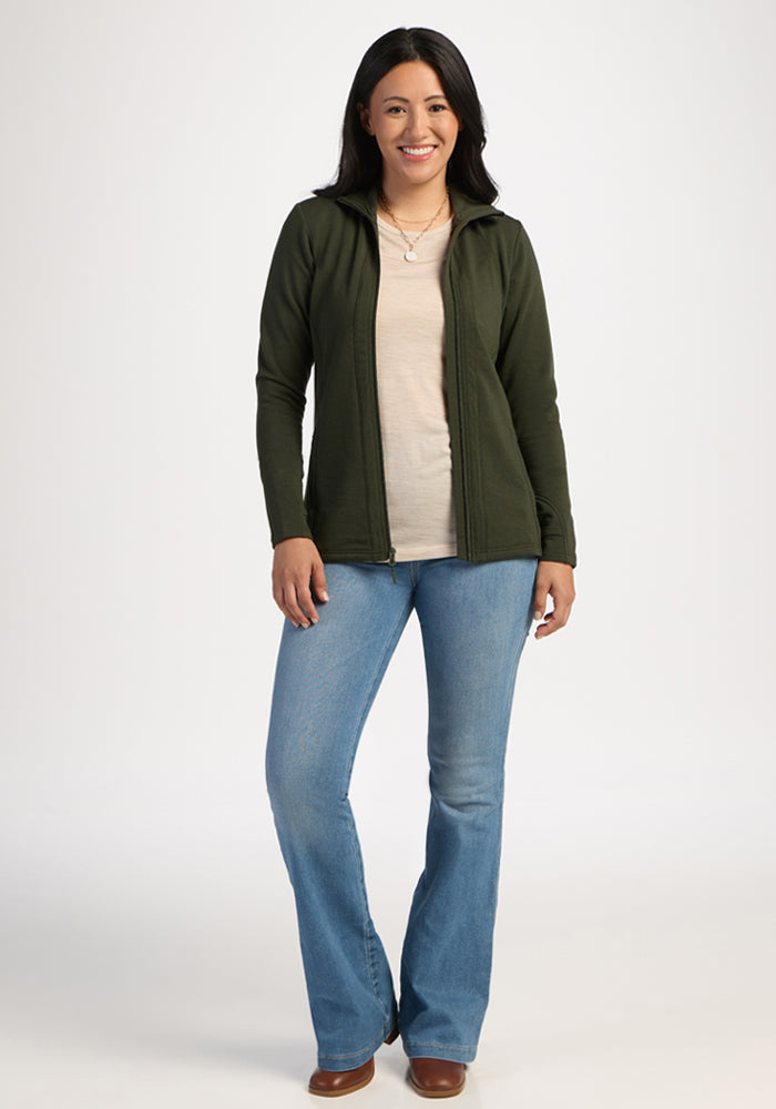 Smiling woman in green jacket (Woolx Finley Zip Up Sweatshirt - Duffel Bag), made with odor-resistant fabric.