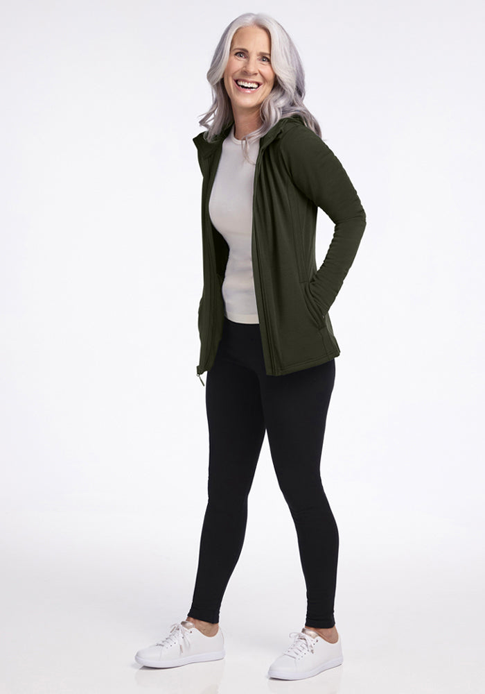 Smiling woman wears the Woolx Zoey Zip Up Hoodie in Duffel Bag, posing against a white background.
