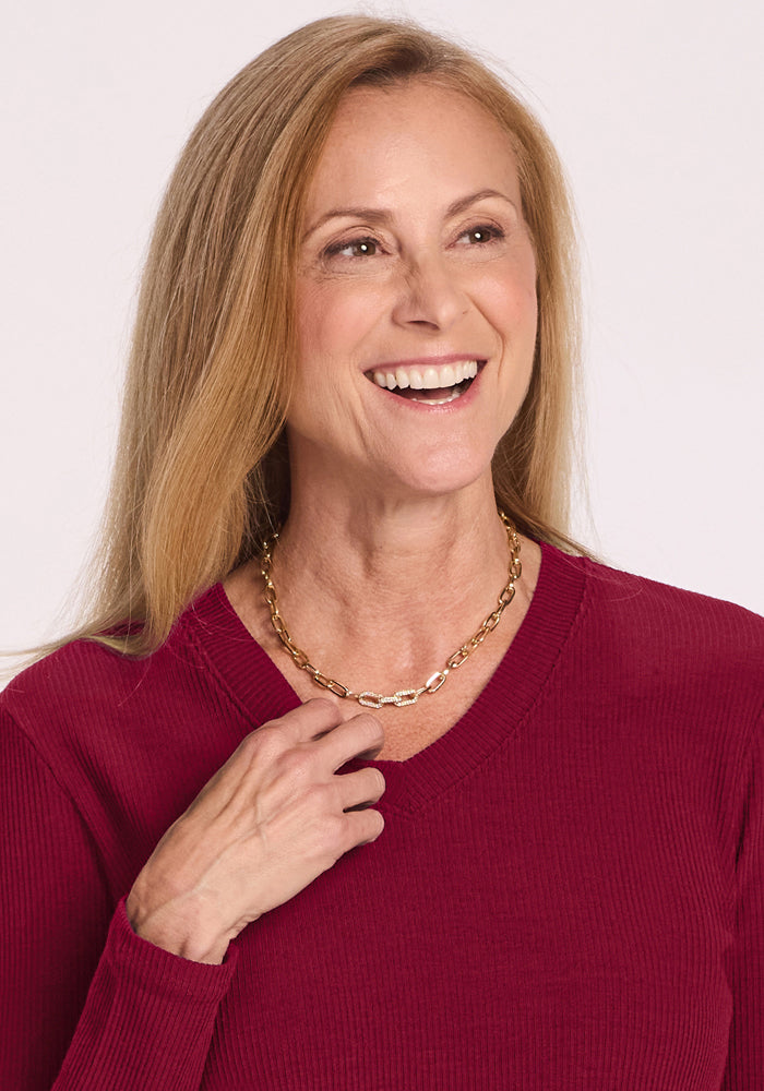 Smiling woman with long blonde hair wears the Woolx Evie Petite Tunic in Beet Red and a gold chain necklace.