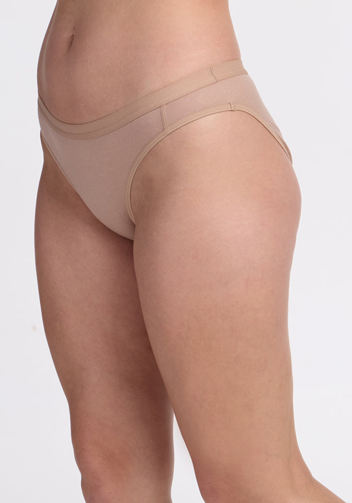 A person models the Woolx Roxie Bikini Underwear in Morning Latte, standing against a plain white background. The cropped image emphasizes the fit, style, and comfort of the DuraLite Merino wool fabric.